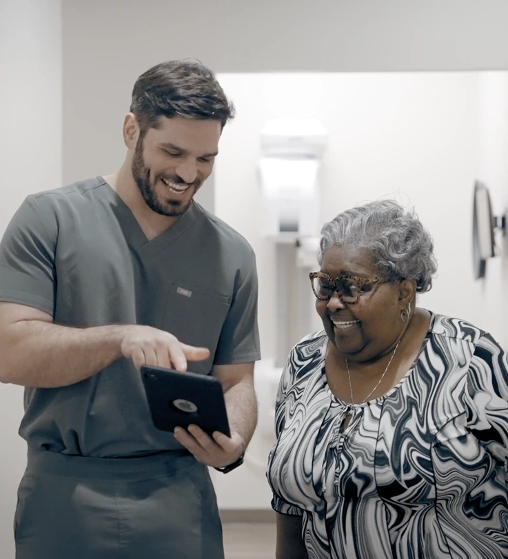 Male dentist showing tablet to senior woman patient in dental office setting.