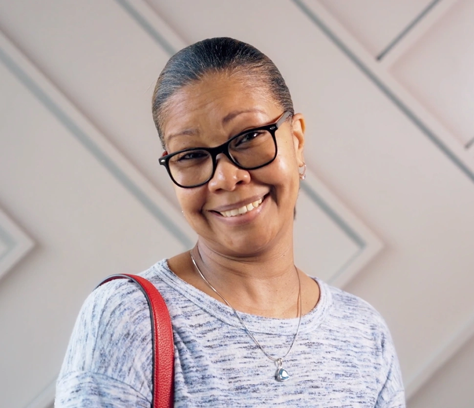 Smiling woman wearing glasses and light blue shirt against geometric wall background